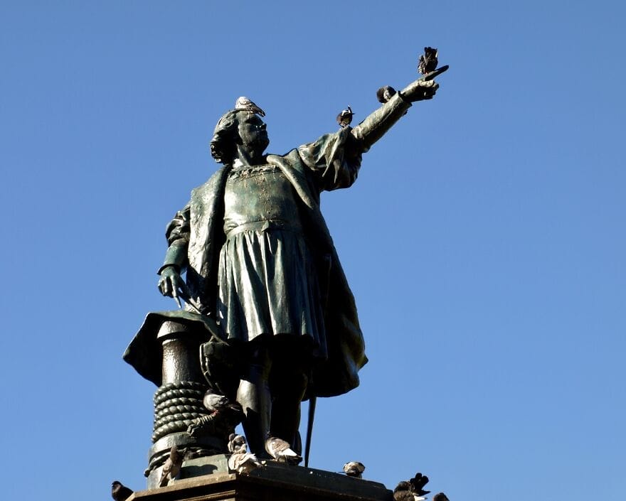 patung christopher columbus dengan merpati bertengger di atasnya