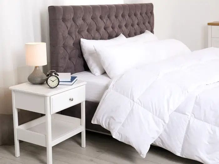 bed bedroom headboard white sheets pillows clock lamp