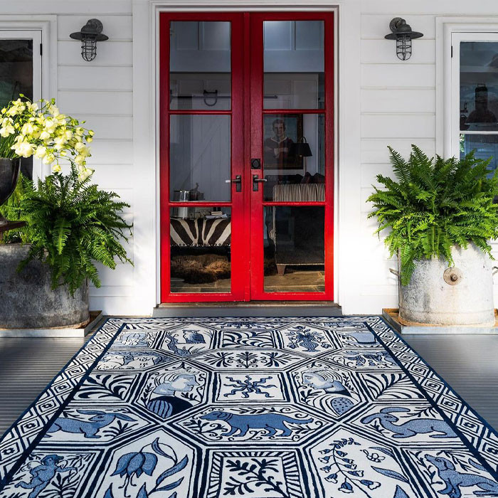 Pintu masuk rumah dengan karpet berpola biru dan pintu merah
