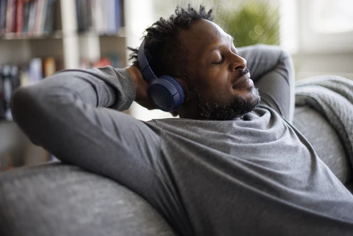 03 young man enjoying music over headphones while relaxing on the sofa at home