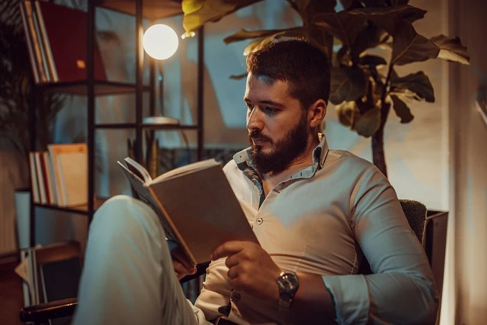 04 man sitting on a chair and reading a book at home at night