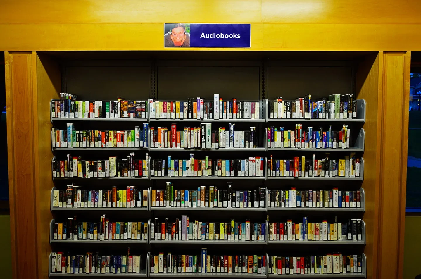 Koleksi audiobook di perpustakaan—opsi mendengar saat bepergian.